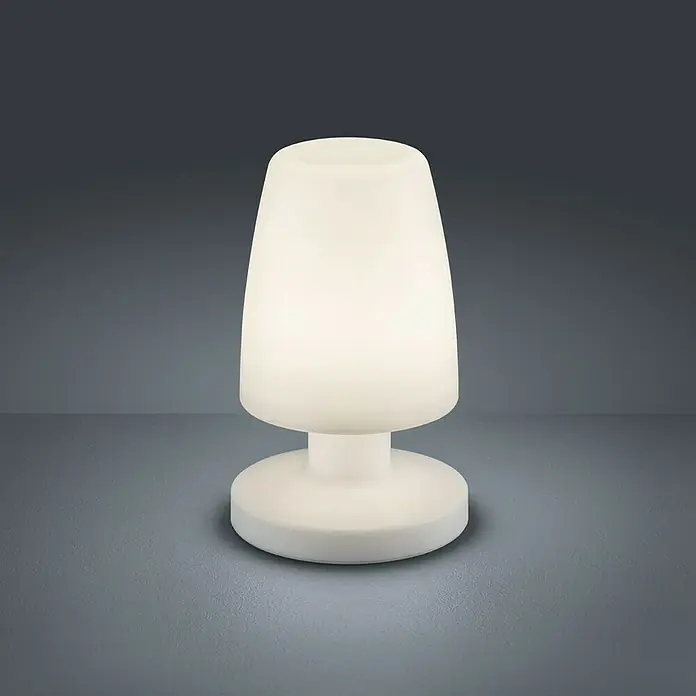 Reality Leuchten Akku-Tischleuchte Dora - 1,5 W, L x B x H: 13 x 13 x 21 cm, Weiß, Warmweiß - Nahaufnahme einer weißen, leuchtenden Tischleuchte mit Kegelförmigem Schirm und rundem Fuß auf einem grauen Tisch.