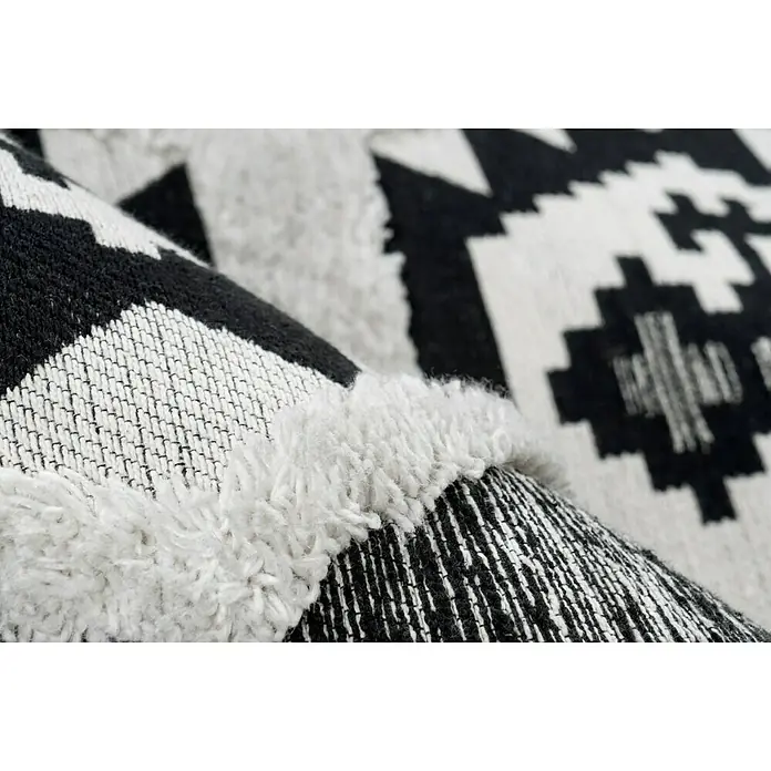 Kayoom Flachgewebeteppich Ethnie II - Grau, 230 x 160 cm, 100 % Baumwolle - Nahaufnahme eines Teppichs mit Fransen und geometrischem Muster in Schwarz und Weiß für ein modernes Zuhause.