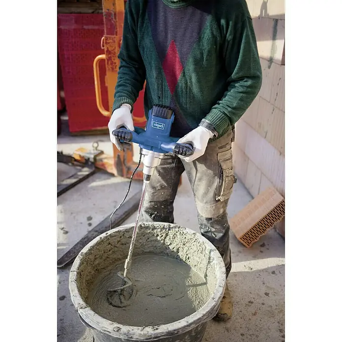 Scheppach Varilla mezcladora de pintura y mortero PM1200 - 1.200 W, Diámetro paleta de mezcla: 120 mm, M 14 - Un trabajador de la construcción mezcla cemento con un mezclador de mortero Scheppach para trabajos de construcción. La máquina es azul.