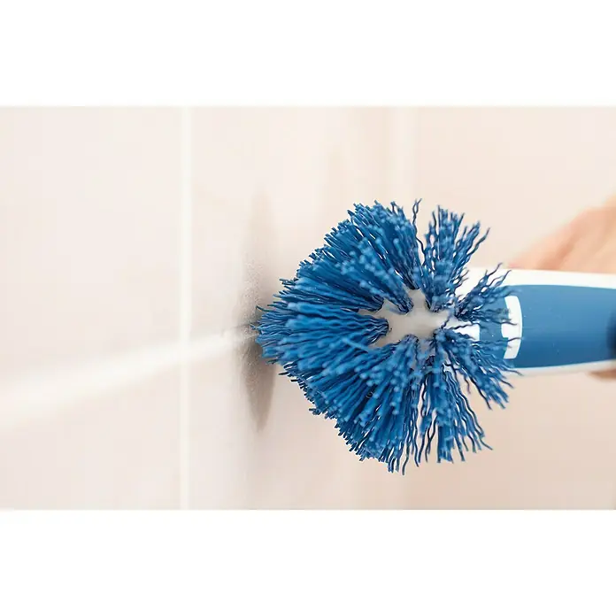 Unger Eckreinigungsbürste - Länge: 20 cm, Material Borsten: Nylon - Nahaufnahme einer blauen Bürste, die gegen eine Badezimmerfliese schrubbt und sich ideal für die Reinigung schwer zugänglicher Stellen eignet.