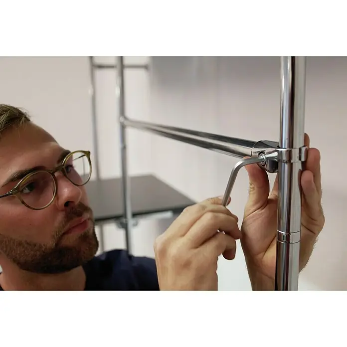 Easy Connect Kleiderstangen-Set - Passend für: Easy Connect Regalsystem, 1.100 mm, Chrom - Mann montiert ein verchromtes Regalsystem mit einem Inbusschlüssel. Einfache Montage für dieses stilvolle Möbelstück.