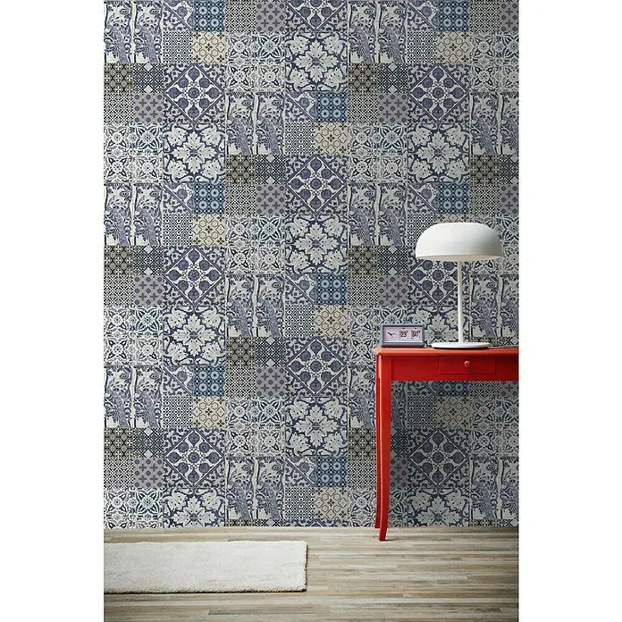 A.S. Création Metropolitan Stories Vliestapete Vintage-Fliese - Lila/Braun, Fliesenoptik, 10,05 x 0,53 m - Wand mit blauen und weißen Mosaikfliesen, roter Tisch mit Lampe und Uhr, heller Teppich auf Holzboden.