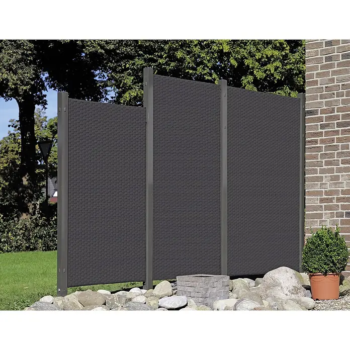 Sichtschutzelement Stockholm - 90 x 180 cm, Anthrazit - Bild einer grauen Sichtschutzwand mit drei Elementen, die im Garten zwischen Steinen und Pflanzen steht.
