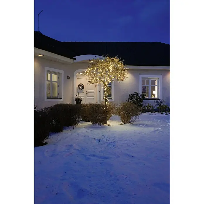 Konstsmide LED-Lichterkette - Innen, Lichtfarbe: Warmweiß, Anzahl Leuchtmittel: 40 Stk., Netzbetrieben - Ein Haus mit der Nummer 65, dekoriert mit einem Baum, der mit warmen Lichtern geschmückt ist, umgeben von einer Schneelandschaft im Winter.