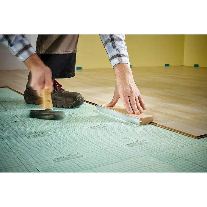 Wolfcraft Schlagholz - L x B x H: 28,1 x 6,2 x 2,4 cm - Ein Handwerker verlegt Laminatboden mit einem Hammer und einem Schlagklotz, um die Dielen passgenau zu verbinden.