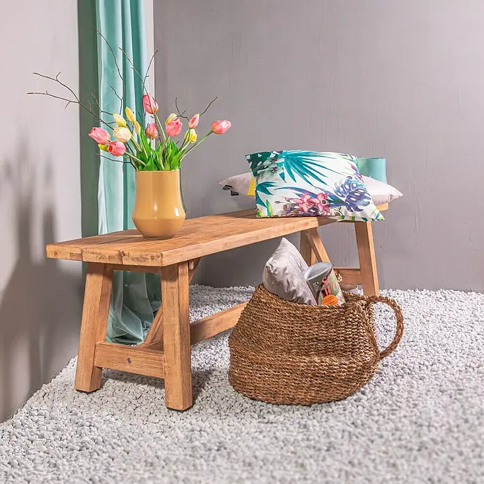 Expo Ambiente Schlaufenbandschal Samtschal Velvet - 135 x 245 cm, 100 % Polyester, Hellgrün - Eine rustikale Holzbank mit einem gelben Tulpenstrauß, Kissen und einem gefüllten Korb auf einem Kiesboden, ideal für den Innenbereich.