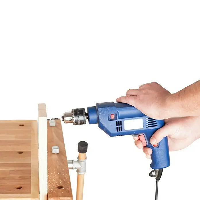 Banco de trabajo - L x An: 1.400 x 500 mm, Altura de trabajo: 830 mm, Carga soportada: 400 kg, Marrón - Primer plano de un taladro azul perforando un trozo de madera. Ideal para proyectos de bricolaje o construcción.