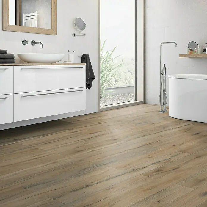 Classen Vinylbodenmuster GreenVinyl Risseiche Dunkel - 300 x 173 x 4 mm, Landhausdiele - Ein Badezimmer mit Holzboden, einem weißen Waschtisch mit Aufsatzwaschbecken und einer freistehenden Badewanne mit Armatur.