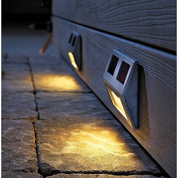 3M Scotch Cinta engomada Extreme - 25 x 76 mm, Negro - Primer plano de luces solares montadas en una pared, que proyectan una luz cálida sobre adoquines de piedra.