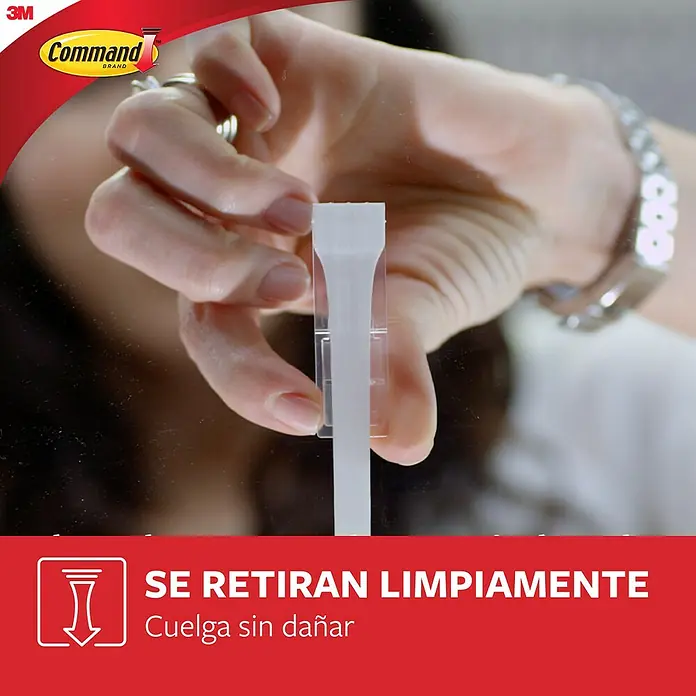 3M Command Gancho para colgar cuadros XL - Plástico, Blanco - Primer plano de una mano aplicando una tira adhesiva Command sobre una superficie lisa.