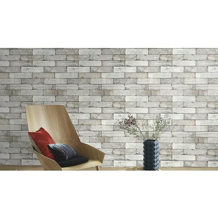 Rasch Vliestapete Factory 2 - Creme, Steinoptik, 10,05 x 0,53 m - Einrichtungsidee mit einem hellen Holzstuhl mit Kissen und einer stilvollen Vase vor einer Backsteinwand.