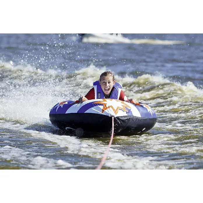 Talamex Funtube Flash - L x B: 136 x 141 cm, Geeignet für: 1 Person, Schnellbefestigung - Eine Frau hat Spaß beim Wassersport mit dem BESTO Wassersport-Schlauchreifen, der mit Sternen verziert ist und für sommerliche Abenteuer sorgt.