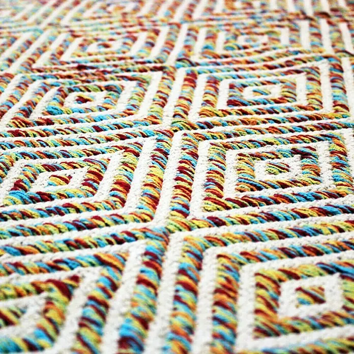 Kayoom Flachgewebeteppich Cocktail 300 - Bunt, 230 x 160 cm, 100% Baumwolle - Detailaufnahme eines bunten Teppichs mit geometrischem Muster, der Textur und Wärme ausstrahlt.
