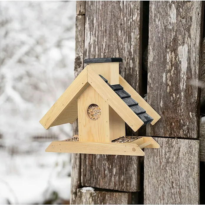 Windhager Vogelfutterhaus Finca - 16,5 x 29 x 25 cm, Braun, Holz, Kiefer - Ein hölzernes Vogelhaus mit Dach und einer runden Öffnung, gefüllt mit Vogelfutter, an einer Holzwand befestigt.