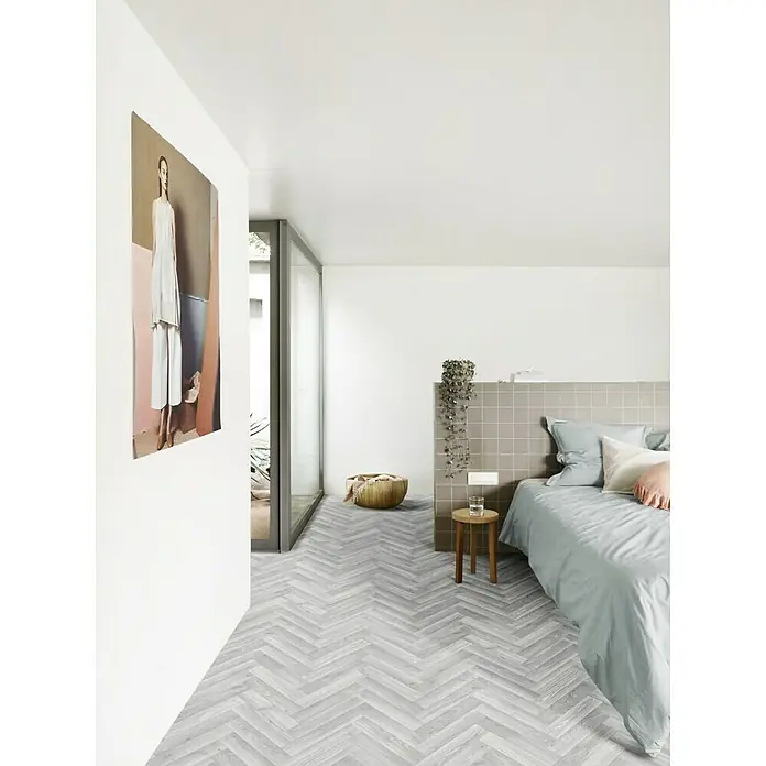 Beauflor PVC-Boden Meterware Artemis - Wood 01, Breite: 400 cm, Hellgrau - Helles Schlafzimmer mit grauen Fischgrätenboden, einem großen Gemälde und einem gemütlichen Bett mit pastellfarbenen Kissen. Minimalistisch und einladend.