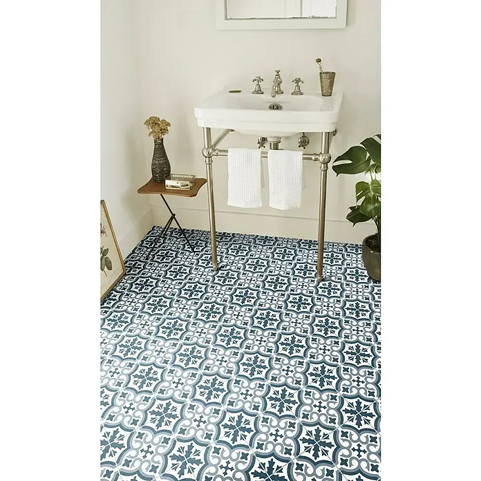 Beauflor PVC-Boden Meterware Orion - 300 cm, Tile 05, Blau/Grau - Ein Badezimmer mit einem Waschtisch und blau gemusterten Bodenfliesen, das eine elegante und stilvolle Atmosphäre schafft.