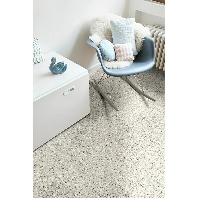 Beauflor PVC-Boden Meterware Calypso - Sonstige, Breite: 400 cm, Grau - Ein helles, einladendes Interieur mit einem stilvollen blauen Schaukelstuhl, dekoriert mit weichen Kissen, auf einem modernen Terrazzoboden.