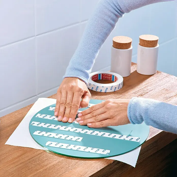 Tesa Powerbond Cinta de doble cara Resistente humedad - 1,9 cm x 5 m, Blanco - Primer plano de tiras adhesivas Tesa aplicadas sobre una superficie redonda. El producto garantiza una sujeción segura y fácil aplicación.