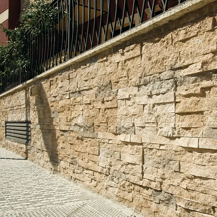 Revestimiento de piedra Salonica Canela - 60 x 30 x 2 cm - Fotografía exterior de una pared revestida con paneles de piedra amarilla decorativa, mostrando una superficie elegante y duradera.