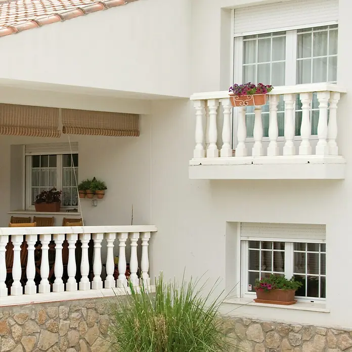 Balaustrada Italia 90 - 12 x 12 x 90 cm, Blanco, Hormigón - Fachada de una casa con balcones adornados con jardineras, creando un ambiente encantador y acogedor.