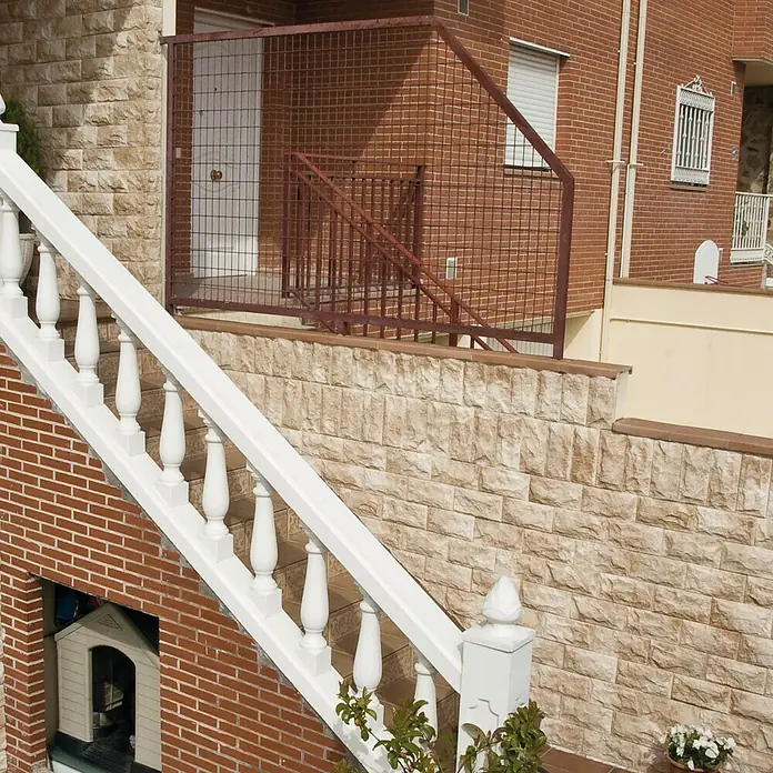 Revestimiento de piedra Teide - 14 x 28 cm, Pardo - Vista detallada de una casa con ladrillo, escalera blanca y barandilla ornamental, resaltando los detalles arquitectónicos.