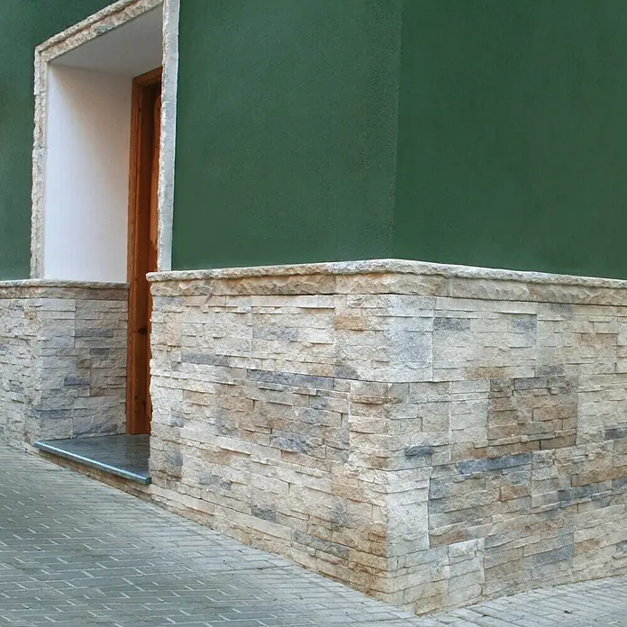 Revestimiento de piedra Salonica Cuarzo - 60 x 30 x 2 cm - Vista exterior de un edificio con revestimiento de piedra decorativa, que realza la base de la fachada con un acento rústico.