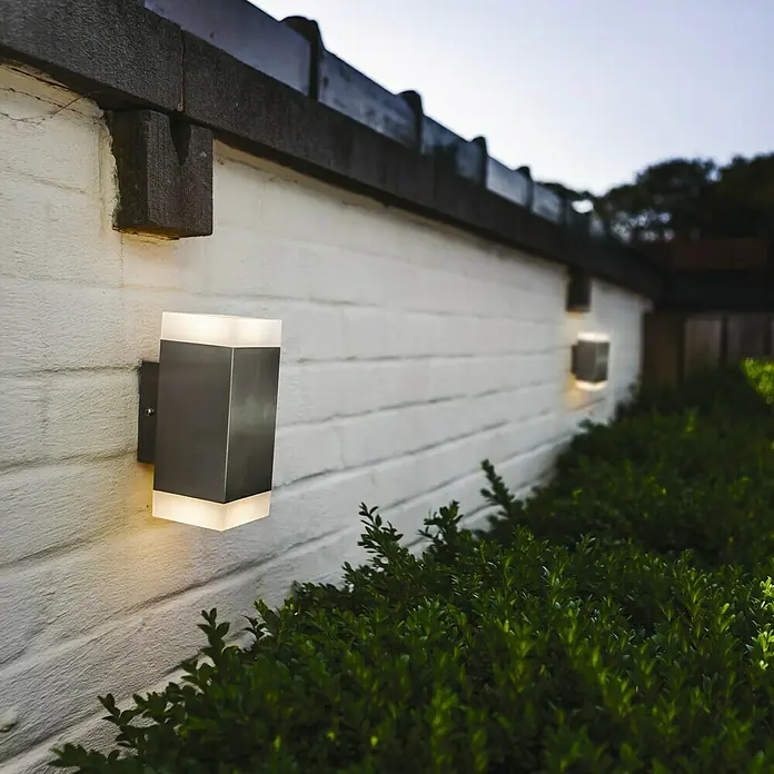 Lutec Aplique exterior LED Bilayer cuadrado - 8 W, 8 x 8 x 19 cm, Plateado, IP44 - Apliques de pared en una pared de ladrillo blanco.
