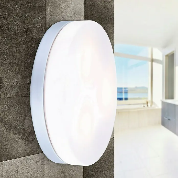 Globo Plafón para pared y techo exterior Vranos 30 - 40 W, L x An x Al: 30 x 30 x 7 cm, Plateado, Opal, IP44 - Una lámpara de techo redonda y blanca está montada en una pared gris en un baño. La luz de la lámpara ilumina la habitación.