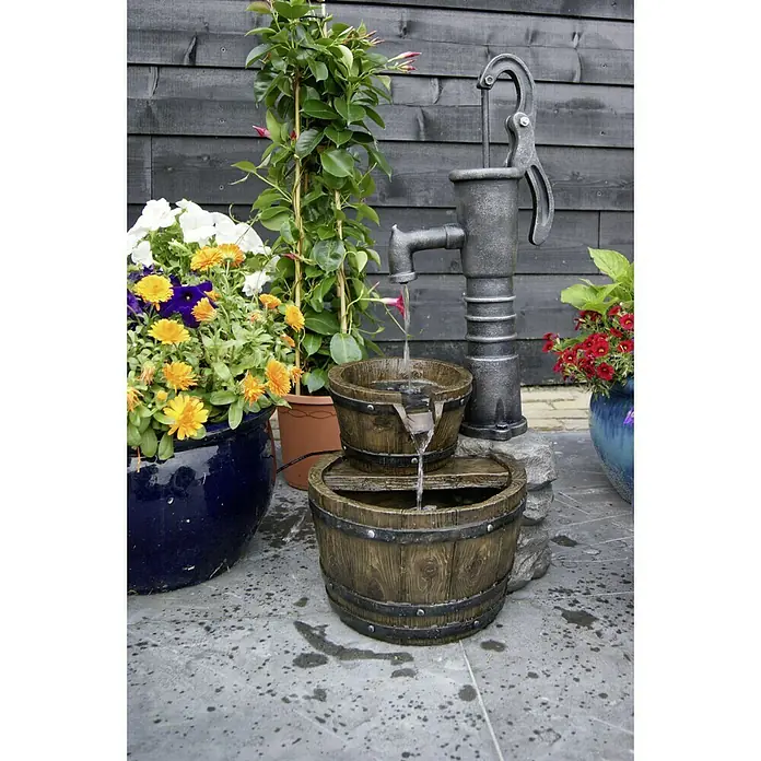 Ubbink AcquaArte Gartenbrunnen Las Vegas - 42 x 36,5 x 80,5 cm, Kunststoff - Dekorative Gartenbrunnen mit zwei Fässern und einer altmodischen Wasserpumpe aus Metall, umgeben von bunten Blumentöpfen.