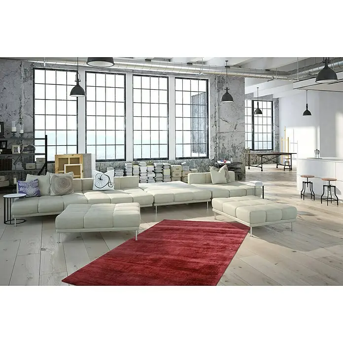 Kayoom Kurzflorteppich Luxury - Violett, 230 x 160 cm, 100 % Viskose - Großzügiges Wohnzimmer mit einem modernen, modularen Sofa und einem tiefroten Teppich, der Wärme und Stil in den Raum bringt.