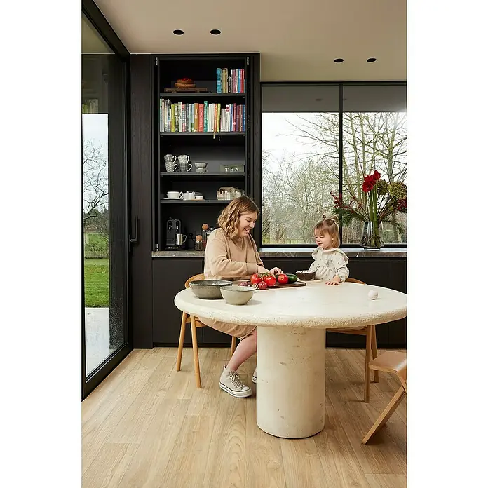 Beauflor PVC-Boden Meterware Athena400 cm, Wood 16, Hellbraun - Eine Frau und ein Kind sitzen an einem runden Tisch aus Beton in einer modernen Küche. Der Tisch ist der Blickfang des Raumes.