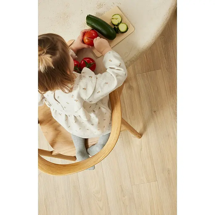 Beauflor PVC-Boden Meterware Athena400 cm, Wood 16, Hellbraun - Ein kleines Mädchen sitzt an einem Tisch und spielt mit Tomaten und Zucchini, ein süßes Outfit und passende Strumpfhose.