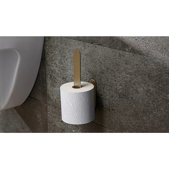Camargue Antwerpen Ersatzpapierrollenhalter - Gold, Matt - Nahaufnahme eines Toilettenpapiers mit Herzmuster, das an einem goldenen Halter an einer strukturierten grauen Wand befestigt ist.