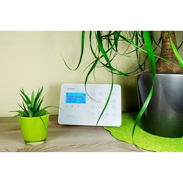 Safe2Home Set de sistema de alarma SP110 - Blanco - Sistema de alarma Safe2Home blanco con pantalla azul que muestra modo alarma casa, fecha, hora y temperatura, sobre superficie de madera.