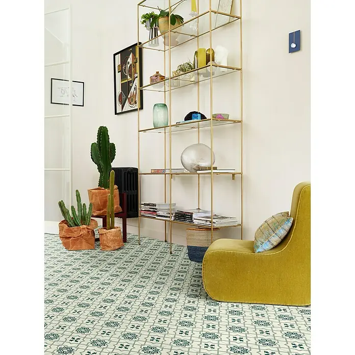 Beauflor PVC-Boden Meterware Calypso - Tile 08, Breite: 400 cm, Olivgrün/Beige - Das Bild zeigt einen Raum mit einem goldenen Regal, einem Senffarbenen Sessel, Kakteen und einem auffälligen Fliesenboden.