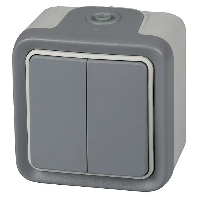 Legrand Plexo Interruptor/Conmutador doble - Gris, Montaje en la pared - Primer plano de un interruptor de luz doble gris con bordes redondeados sobre un fondo blanco.