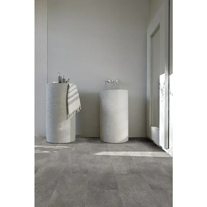 Beauflor PVC-Boden Meterware Themis - Sonstige, Breite: 400 cm, Dunkelgrau - Modernes Badezimmer mit zwei Waschbecken aus Beton, grauen Fliesen und einem Handtuch. Die minimalistische Gestaltung schafft eine ruhige Atmosphäre.