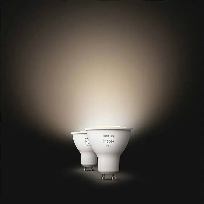 Philips Hue Smart-LED-Lampe White - GU10, Dimmbar, Warmweiß, 400 lm, 4,2 W, 2 Stk. - Zwei Philips Hue White GU10 Lampen strahlen helles, warmes Licht in einem dunklen Raum aus und erhellen die Umgebung sanft.