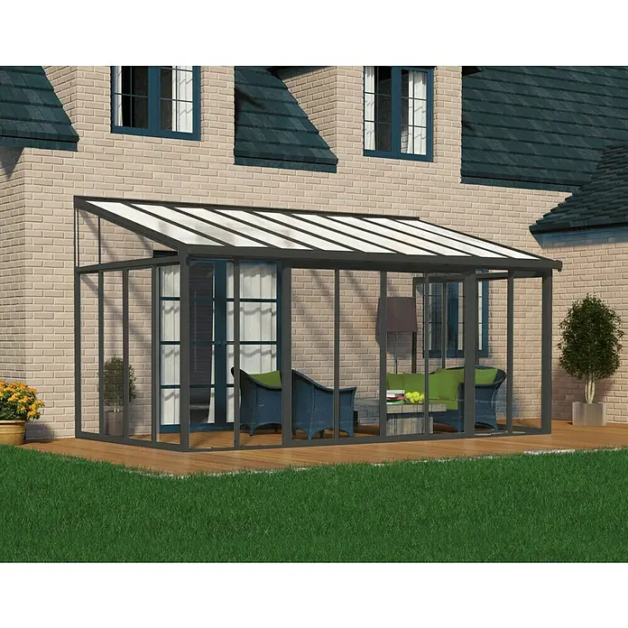 Palram – Canopia Wintergarten San Remo - B x T x H: 5,46 x 3 x 3,1 m, Anthrazitgrau - Ein Wintergartenanbau mit gläsernen Wänden und einem transparenten Dach bietet einen hellen und einladenden Raum im Freien.
