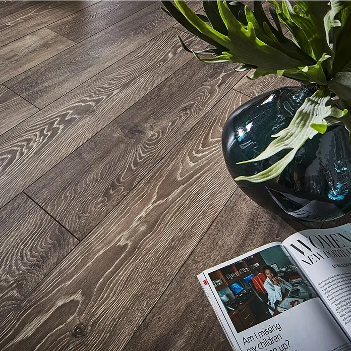 MyStyle MyArt Laminat - Earthen Oak, Landhausdiele, 1.285 x 192 x 12 mm - Nahaufnahme eines Laminatbodens mit Holzmuster, einer Vase mit Pflanze und einer Zeitschrift, die auf dem Boden liegt.