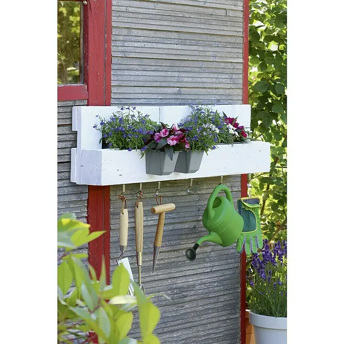 Geli Pflanzkasten-Einsatz Easy - Außenmaß (L x B x H): 10 x 10 x 10 cm, Kunststoff, Betongrau - Das Foto zeigt eine weiße Pflanzkiste mit Gartenwerkzeugen, die an einer grauen Holzwand hängen und mit bunten Blumen bepflanzt sind.