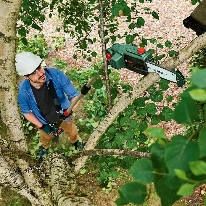 Bosch Power for All 18V Akku-Hochentaster UniversalChainPole 18 - 18 V, Li-Ionen, Ohne Akku - Mann, der einen Bosch Hochentaster zum Beschneiden von Ästen verwendet, mit Sicherheitsausrüstung für sichere Gartenarbeit.