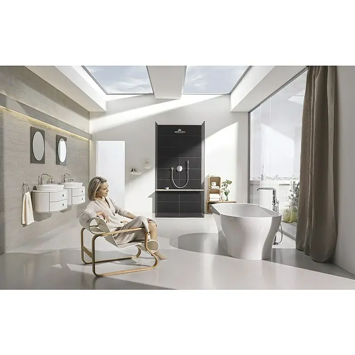 Grohe Essence New Waschtischarmatur - Chrom, Glänzend - Badezimmer mit Badewanne und Armatur vor einem Fenster mit Vorhang. Helle Farben dominieren den Raum mit zwei Dachfenstern.