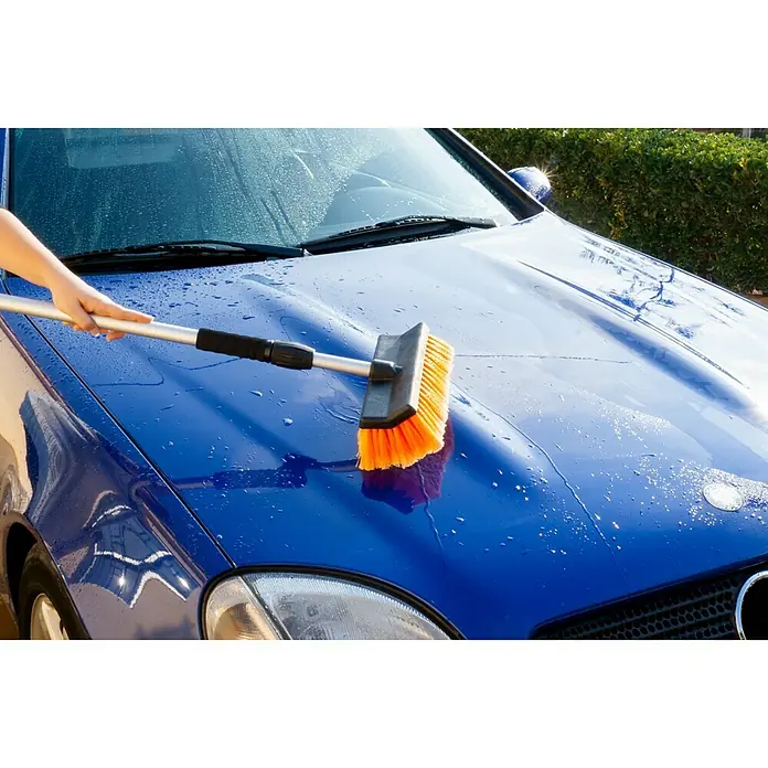 Cepillo para automóviles - Telescópico - Un cepillo de lavado de coches telescópico limpia el capó de un coche azul para que vuelva a brillar. Un accesorio de limpieza fantástico.