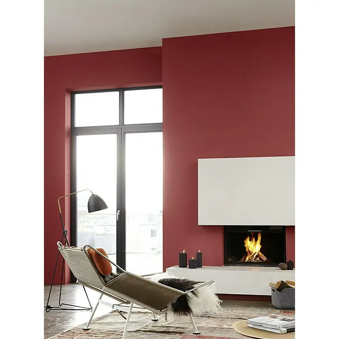 Alpina Wandfarbe Feine Farben - Befreiter Feuervogel, Matt, 2,5 l, Konservierungsmittelfrei - Wohnzimmer mit roter Wand, modernem Kamin und einem stylischen Loungesessel unter einer Bogenlampe. Gemütliches Ambiente.