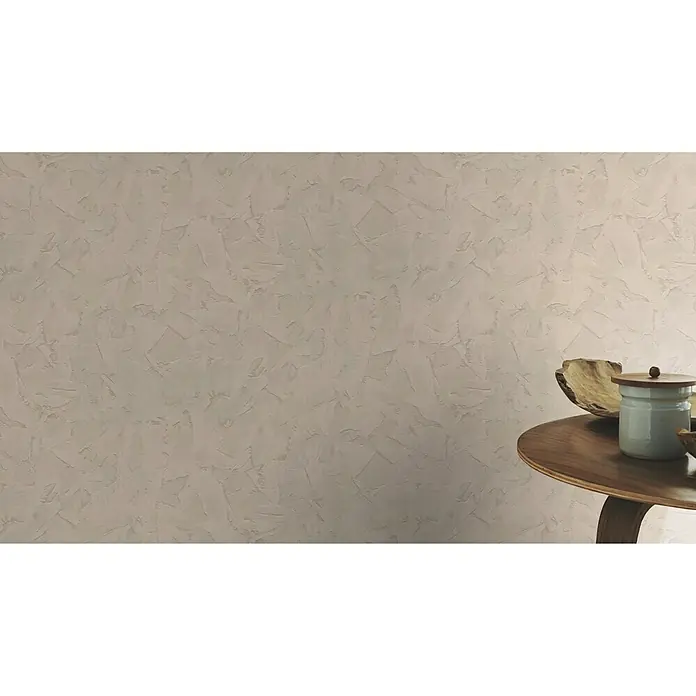 Rasch Vliestapete Putzoptik in Wischtechnik - Taupe, Steinoptik, 10,05 x 0,53 m - Nahaufnahme einer Wand mit dekorativer Spachteltechnik und einem kleinen Holztisch mit Schale und Dose.