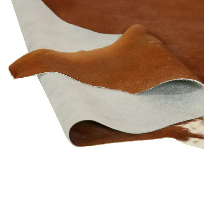 Esbeco Kuhfell - Braun/Weiß, 100 % Echtfell - Detailaufnahme einer braun-weißen Kuhfellmatte, die die Textur und das Muster des Materials hervorhebt.