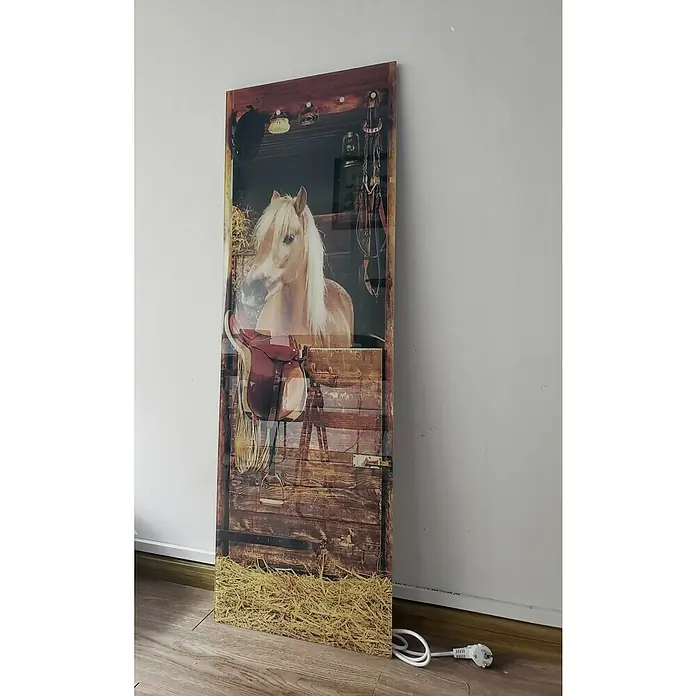 Papermoon Infrarot-Glasbildheizkörper Riding Horse - 400 x 1.200 mm, 500 W - Ein langes, rechteckiges Bild, das ein Pferd in einer Stallbox mit Sattel zeigt, dient als dekorative und einzigartige Wandheizung.