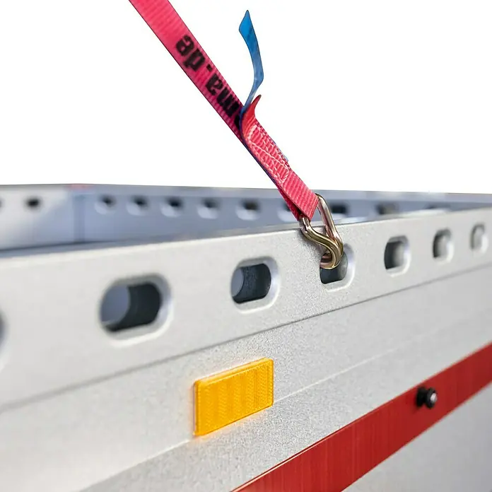 Stema Anhänger BH-R 750 Hochplane - Nutzlast: 608 kg, Einachser, Ungebremst - Detailansicht eines Anhängers mit Zurrgurt, der an einem Loch befestigt ist. Reflektor und rote Linie sichtbar.