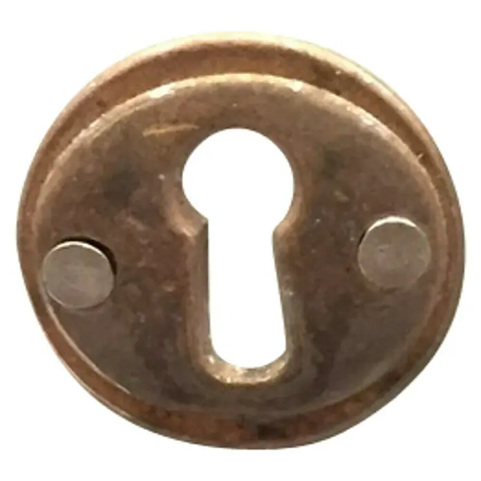 Stabilit Schlüsselschild - Ø x H: 28 x 2 mm - Nahaufnahme eines verzierten, goldenen Schlüssellochs mit zwei Befestigungsnieten, ideal für antike Möbel oder Türen.